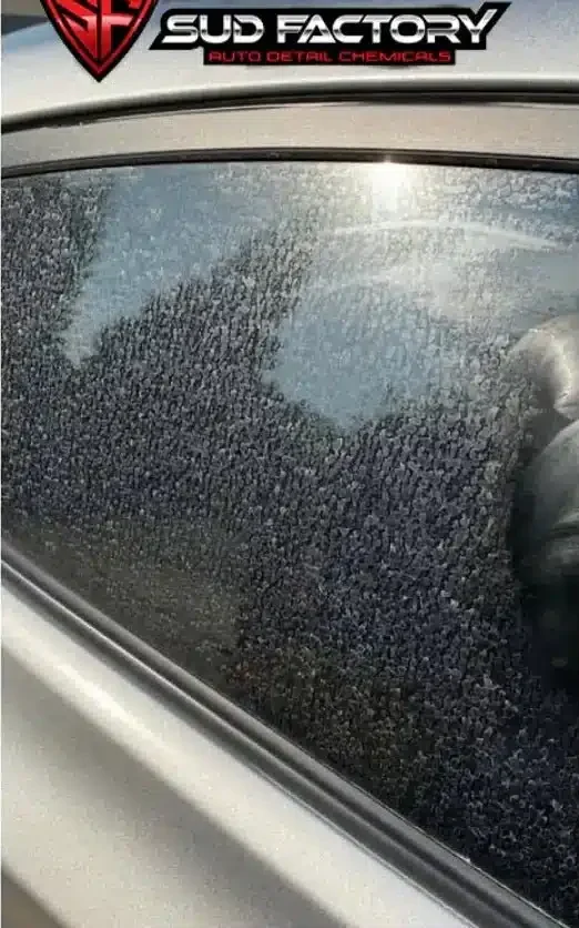 Car side window covered in hard water spots